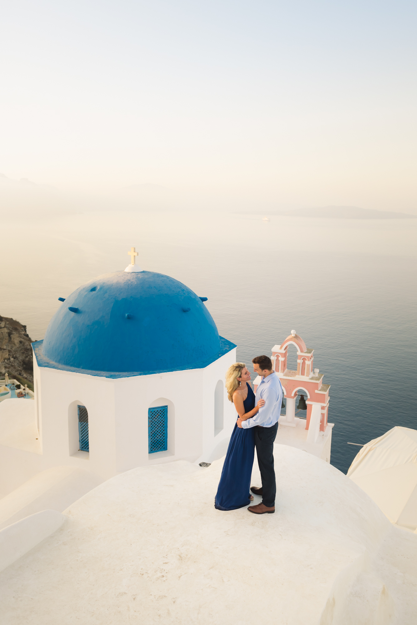 Couple on the rooftop, next to the blue domes in Oia