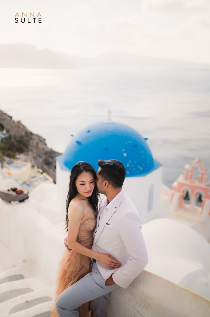 Santorini blue domes. Instagram spot in Oia, Greece with a couple posing.